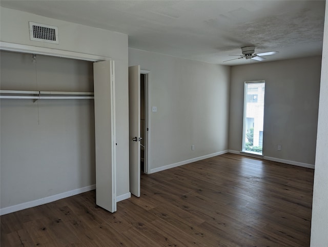 unfurnished bedroom with a closet, dark wood-type flooring, and ceiling fan