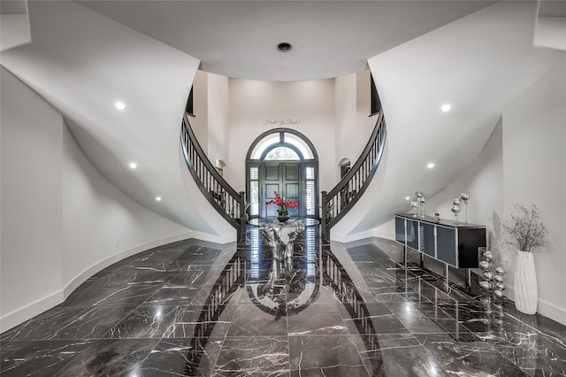 foyer with a towering ceiling and dark tile floors