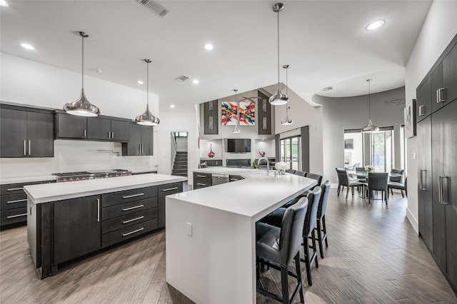 kitchen featuring decorative light fixtures, stainless steel appliances, a large island, a high ceiling, and hardwood / wood-style flooring