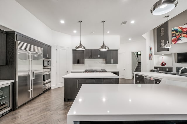 kitchen featuring a center island, built in appliances, pendant lighting, wine cooler, and light wood-type flooring