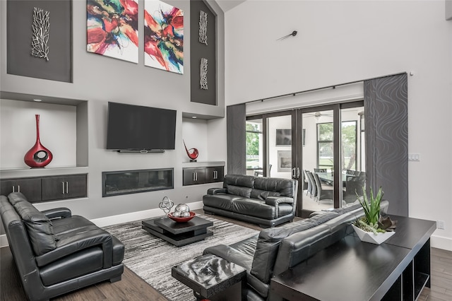 living room with a high ceiling and dark wood-type flooring