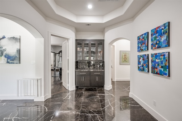 corridor with dark tile floors and a tray ceiling