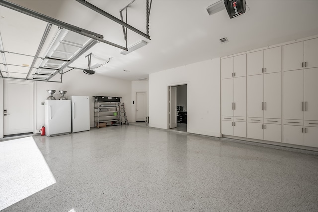 garage featuring white fridge and a garage door opener