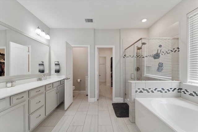 full bathroom featuring vanity, shower with separate bathtub, and toilet