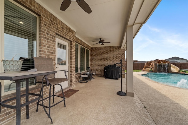 view of patio featuring a fenced in pool, area for grilling, pool water feature, and ceiling fan