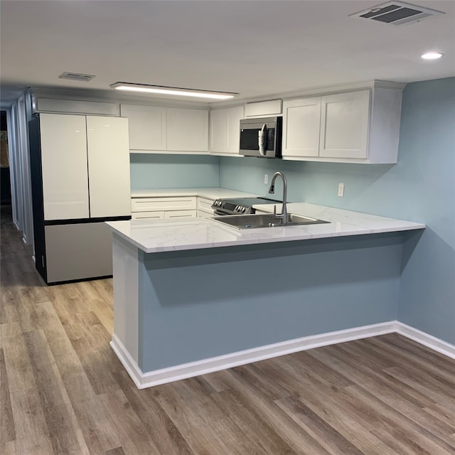 kitchen with light hardwood / wood-style flooring, sink, stainless steel appliances, and kitchen peninsula