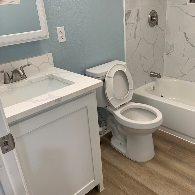 full bathroom featuring tiled shower / bath, toilet, vanity, and hardwood / wood-style floors