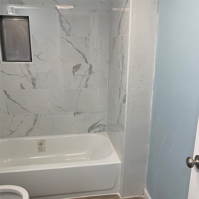 bathroom with tiled shower / bath combo and toilet