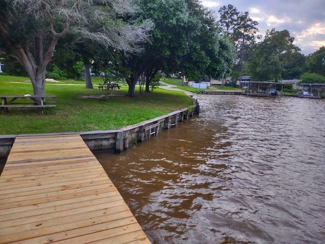 view of dock featuring a lawn and a water view