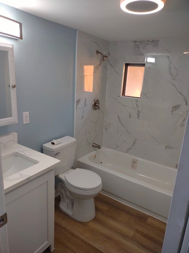 full bathroom featuring tiled shower / bath, vanity, hardwood / wood-style floors, toilet, and a textured ceiling