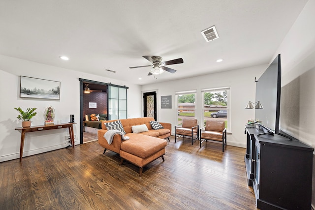 living room featuring a barn door, ceiling fan, and dark wood-type flooring