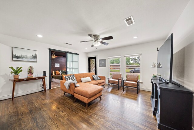 living room featuring dark hardwood / wood-style flooring, a barn door, and ceiling fan