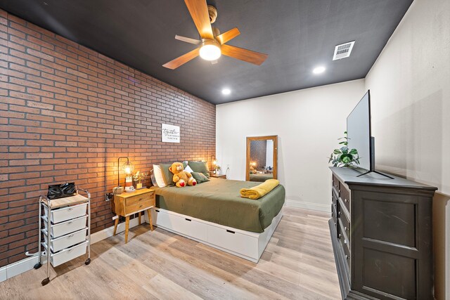 bedroom with ceiling fan, brick wall, and light wood-type flooring