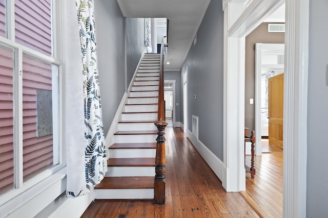 staircase featuring ornamental molding and dark hardwood / wood-style flooring