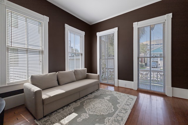 living room with wood-type flooring, plenty of natural light, and ornamental molding