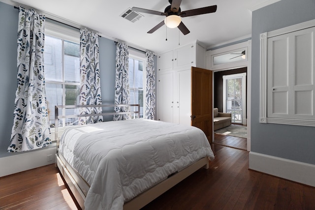 bedroom featuring ornamental molding, multiple windows, ceiling fan, and dark wood-type flooring