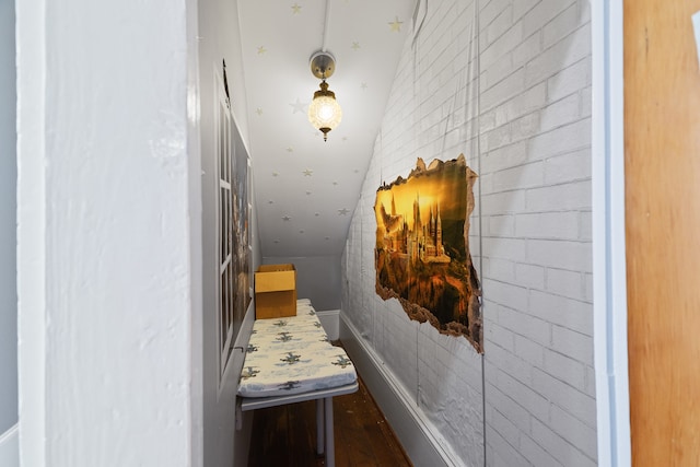 corridor with hardwood / wood-style floors and vaulted ceiling