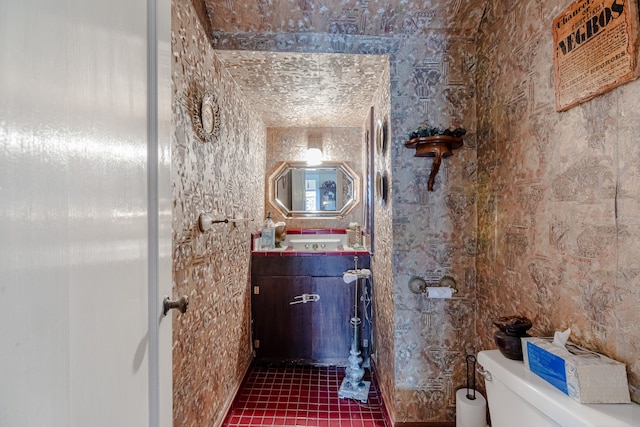 bathroom with tile walls, vanity, toilet, and tile flooring