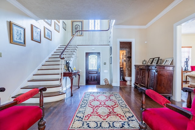 entrance foyer with dark hardwood / wood-style floors, a textured ceiling, and ornamental molding