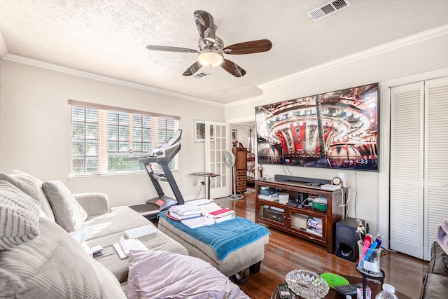 living room featuring a textured ceiling, ceiling fan, dark wood-type flooring, and ornamental molding