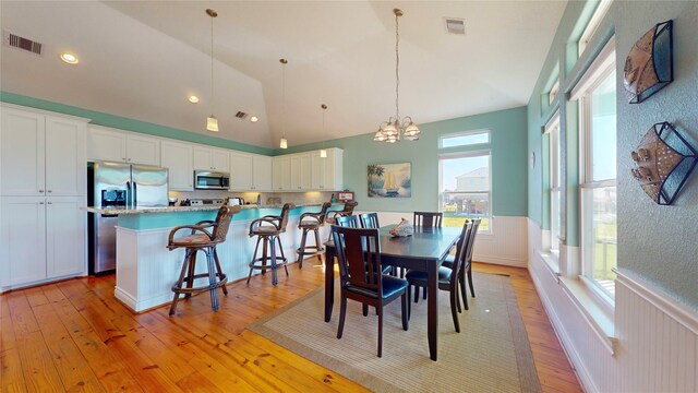 dining room with high vaulted ceiling, light hardwood / wood-style floors, and a chandelier