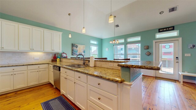 kitchen with sink, light hardwood / wood-style floors, backsplash, decorative light fixtures, and light stone countertops