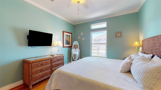 bedroom featuring hardwood / wood-style floors, ornamental molding, multiple windows, and ceiling fan