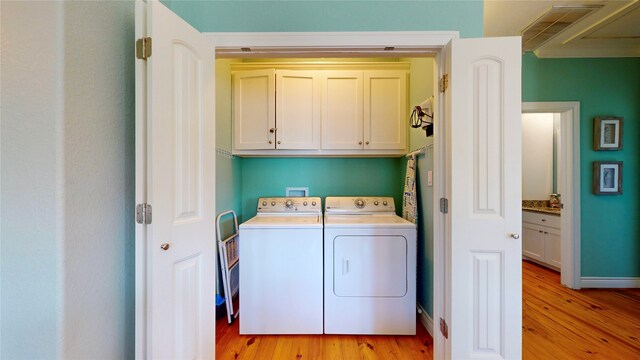 washroom featuring light hardwood / wood-style floors, cabinets, washer hookup, and separate washer and dryer