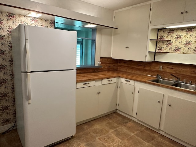 kitchen featuring tile patterned flooring, white cabinets, sink, and white fridge