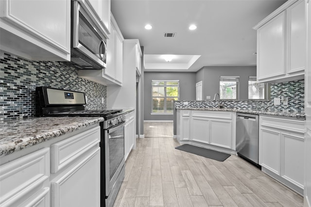 kitchen featuring white cabinetry, stainless steel appliances, and light stone counters