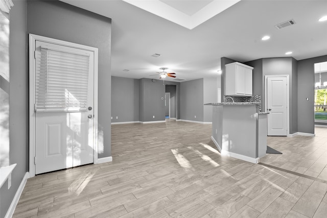 kitchen featuring light stone counters, ceiling fan, light hardwood / wood-style flooring, and white cabinets