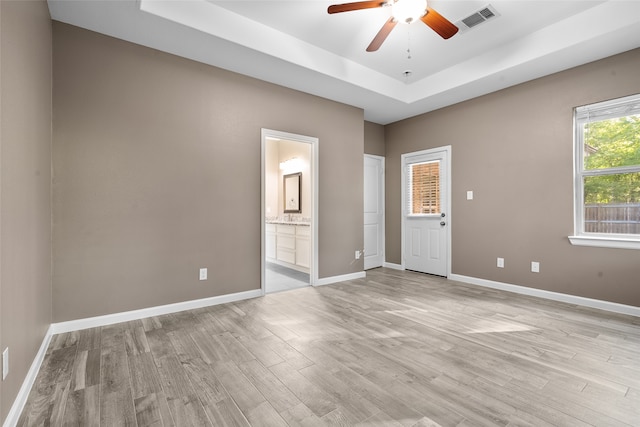 spare room with a raised ceiling, ceiling fan, and light hardwood / wood-style flooring