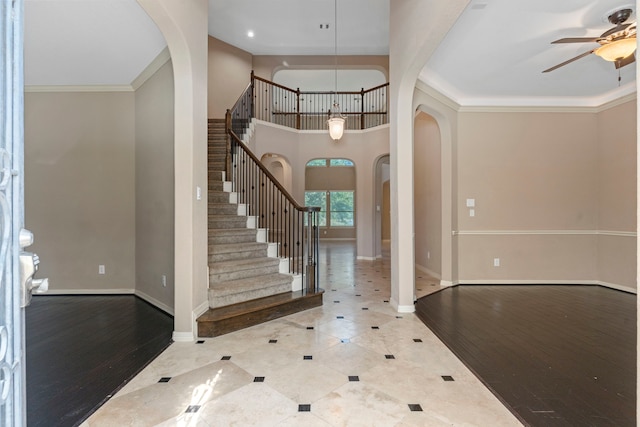 tiled foyer featuring a towering ceiling, crown molding, and ceiling fan