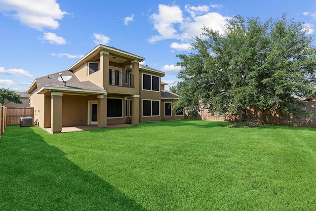 back of property featuring a yard, a balcony, and central AC unit