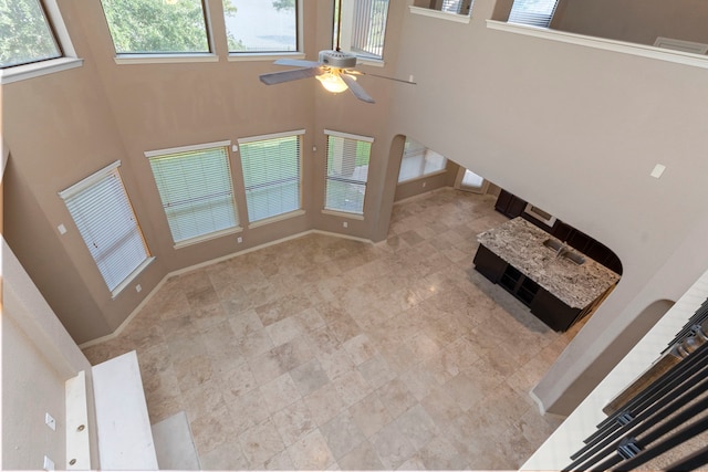 unfurnished living room featuring a high ceiling, ceiling fan, and tile floors