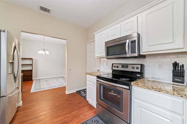 kitchen featuring white cabinets, backsplash, an inviting chandelier, stainless steel appliances, and light hardwood / wood-style floors