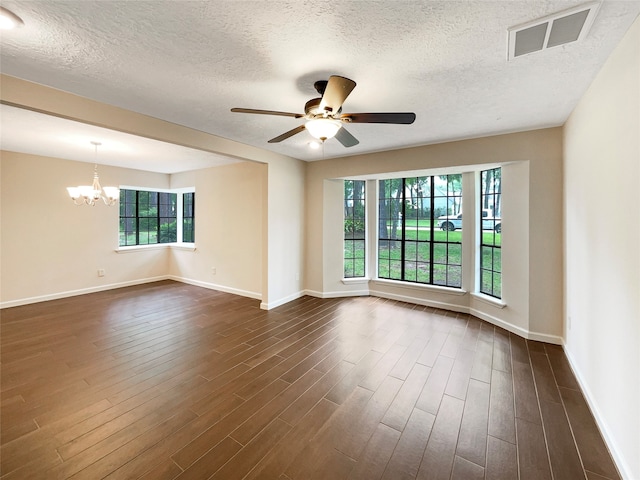 spare room featuring dark hardwood / wood-style flooring, a healthy amount of sunlight, and ceiling fan with notable chandelier