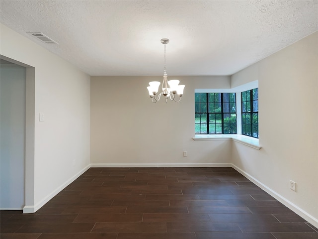 spare room with a chandelier, dark hardwood / wood-style flooring, and a textured ceiling