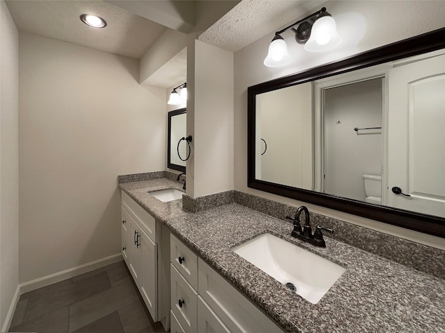 bathroom with toilet, tile floors, a textured ceiling, and double sink vanity