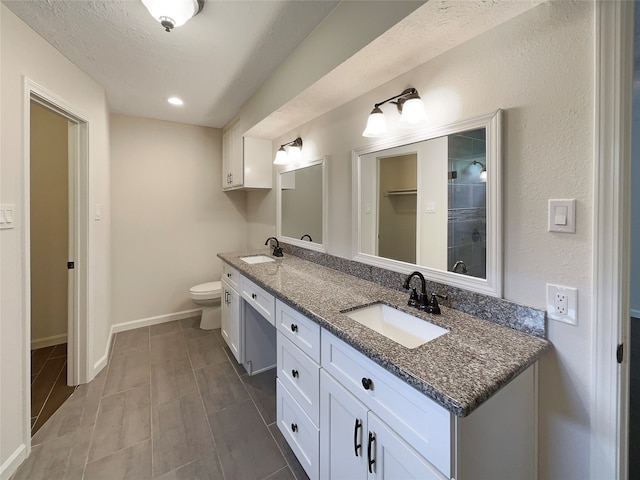 bathroom with tile flooring, double vanity, toilet, and a textured ceiling