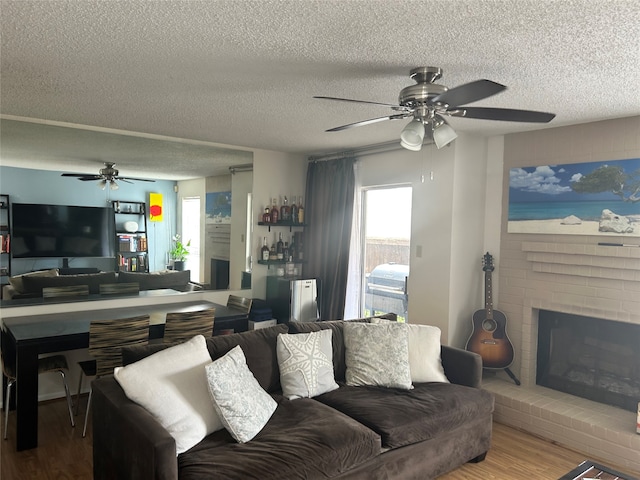 living room featuring a textured ceiling, a brick fireplace, ceiling fan, and hardwood / wood-style floors