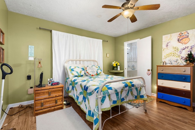 bedroom featuring ensuite bath, ceiling fan, hardwood / wood-style flooring, and a textured ceiling