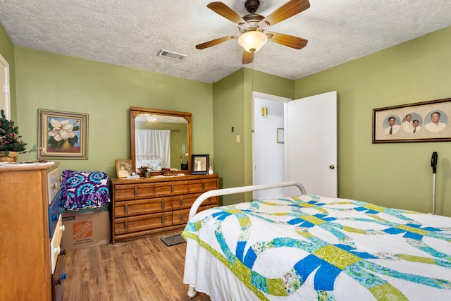 bedroom featuring ceiling fan, hardwood / wood-style flooring, and a textured ceiling