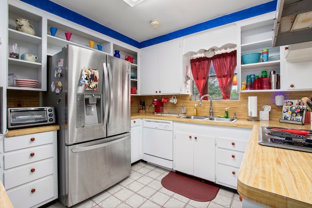 kitchen featuring light tile floors, sink, dishwasher, backsplash, and stainless steel fridge