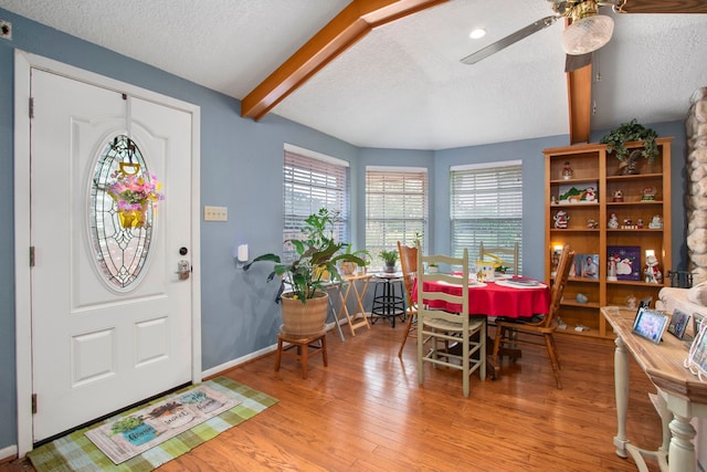 foyer entrance with hardwood / wood-style flooring, beam ceiling, ceiling fan, and a textured ceiling