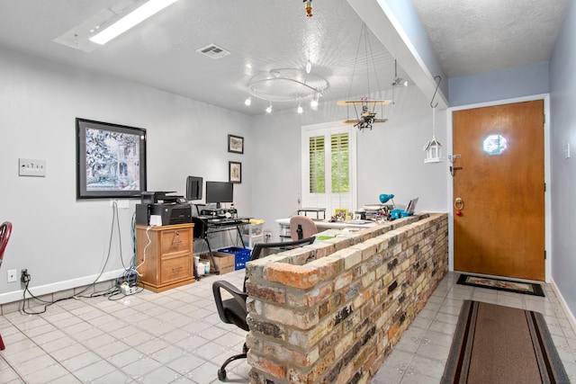 home office featuring light tile floors and a textured ceiling