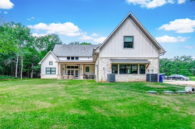 rear view of house with central AC and a lawn