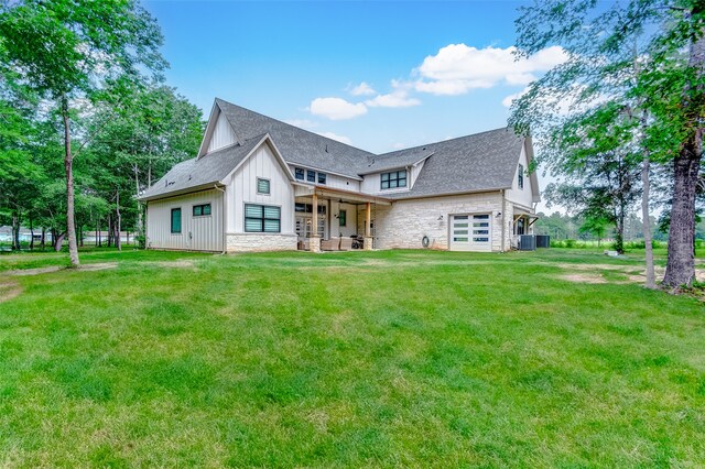 rear view of property with central AC unit and a lawn