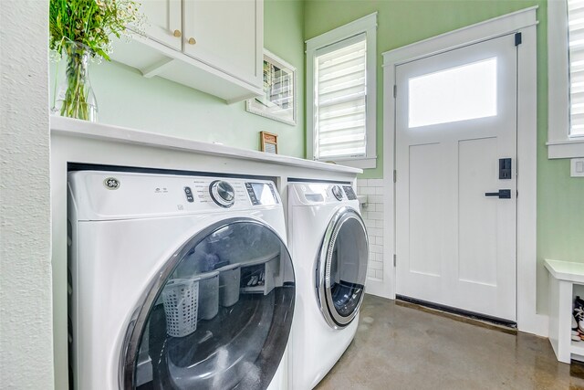 clothes washing area featuring cabinets and washer and clothes dryer