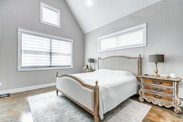 bedroom with concrete flooring and high vaulted ceiling